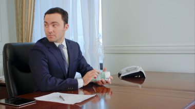 Başarılı genç işadamı ofiste meslektaşım ile konuşma euro faturaları sayar