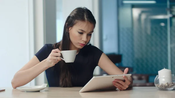 Молода жінка використовує цифровий планшет під час пиття кави або чаю в кафе — стокове фото