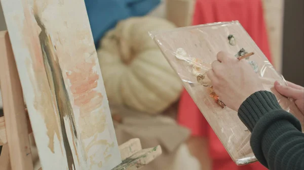 Joven artista masculino mezclando colores en la paleta y la pintura — Foto de Stock