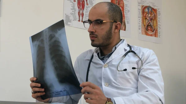 Koncentrált fiatal férfi orvos megvizsgálja a mellkas xray kép — Stock Fotó