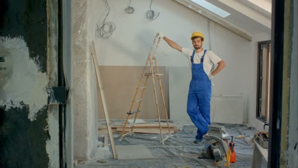 Junger Handwerker oder Bauarbeiter, der im Haus steht und in die Kamera schaut — Stockvideo