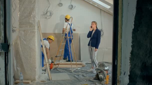 Frau telefoniert mit Bauunternehmern, die auf Baustelle diskutieren — Stockvideo