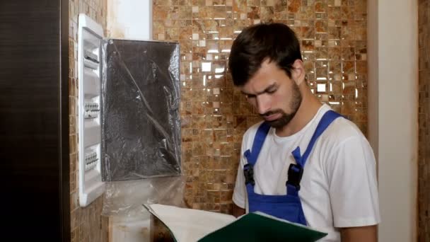 Constructor electricista adulto joven ingeniero atornillando equipos en caja de fusibles — Vídeo de stock