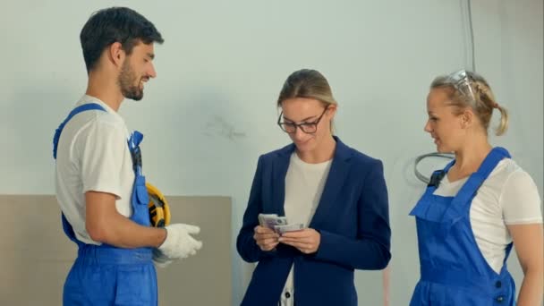 Supervisore del cantiere dare un denaro o pagare ai costruttori per il lavoro in piedi presso il cantiere — Video Stock