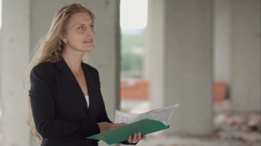 Taslaklar büyük inşaat sitesini ziyaret ederken okuyan kadın mimar