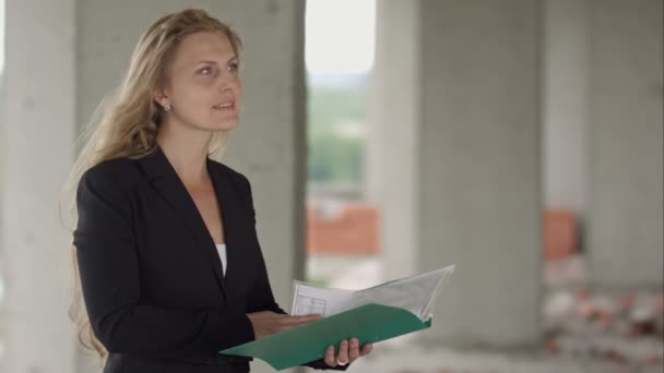 Женщина-архитектор изучает черновики во время посещения большой строительной площадки — стоковое видео