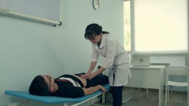 Kadın doktor erkek hastanın karın muayenesi yapıyor