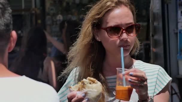 Junges Touristenmädchen isst Streetfood auf dem Stadtmarkt — Stockvideo