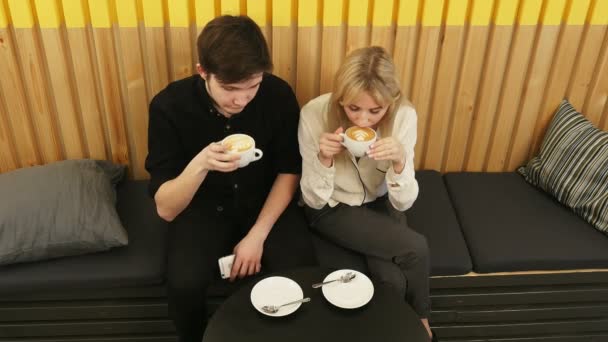 Jeune couple boit du café et parle tout en étant assis au café — Video