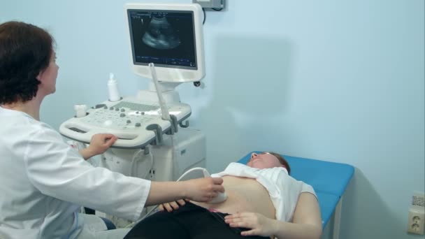 Sonógrafa que sostiene un transductor de ultrasonido para diagnosticar la condición de una mujer embarazada — Vídeo de stock