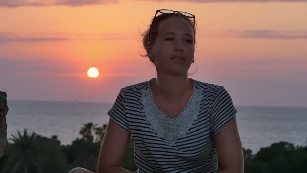 Mladá žena sedí v blízkosti moře a těší na západ slunce — Stock video