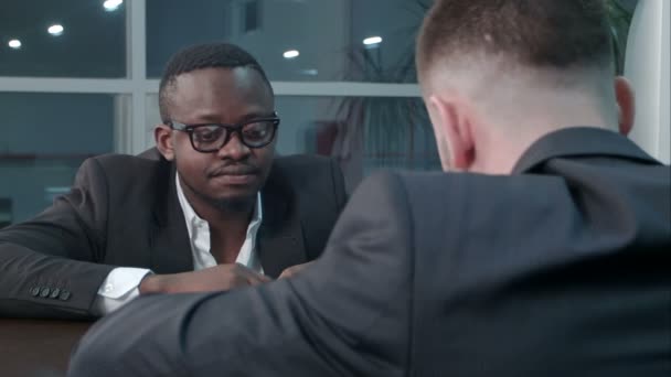 Pensive afro-american and caucasian businessmen working through papers and discussing financial report having concentrated looks, sitting close to each other — Stock Video