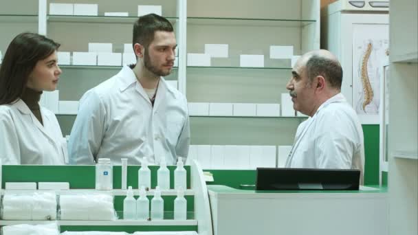 Äldre apotekspersonal och assistenter som talar allvarligt apotek receptionen — Stockvideo