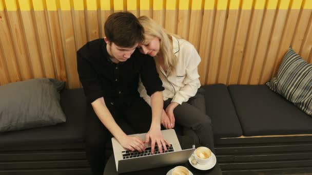 Fristående par använder bärbar dator i kafé — Stockvideo