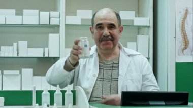 Tablet veya hap ile boş bir beyaz etiket bir hastalık ve fotoğraf makinesi göz tedavisi için bir şişe tutan doktor gülümseyen