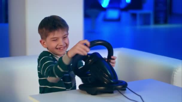 해피 흥분 레이싱 휠와 비디오 게임을 재생 하는 어린 소년 — 비디오