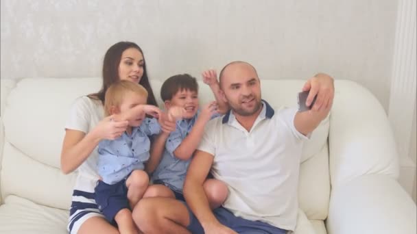 Smiling family taking funny selfies sitting on the sofa — Stock Video