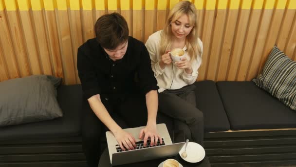 Bokovky pár sedí incafe pití kávy pomocí přenosného počítače — Stock video