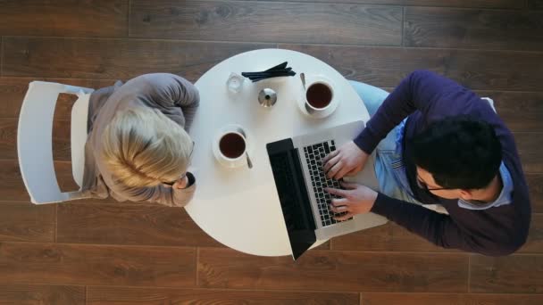 Партнеры, наслаждающиеся работой в ярком современном кафе, женщина с телефонным звонком, мужчина, работающий на ноутбуке — стоковое видео