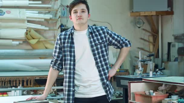 Porträt eines jungen männlichen Arbeiters, der in der Werkstatt steht und ernst in die Kamera blickt — Stockvideo