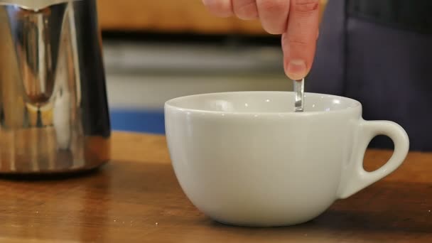 Skakar mjölk i starkt svart kaffe med en sked — Stockvideo