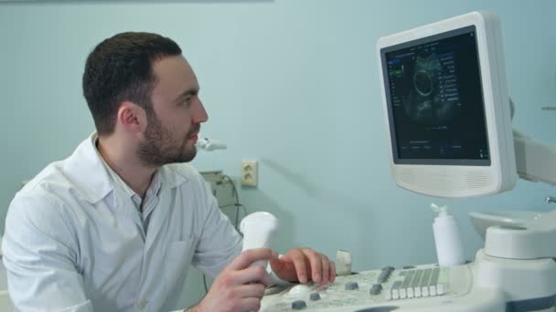 Concentrated male doctor looking at ultrasound scan results — Stock Video