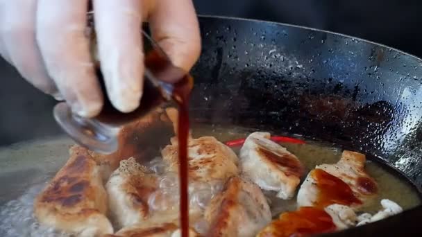 Наливание соуса на жареные пельмени в кастрюле — стоковое видео