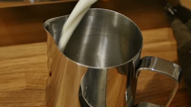 Barista hälla mjölk från stora genomskinliga burken till metall mjölk kannan — Stockvideo