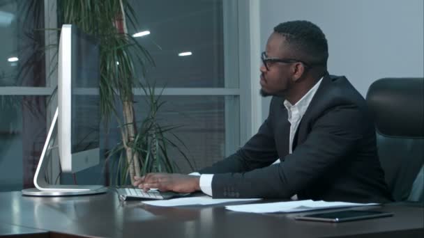 Красивый афро-американский бизнесмен, работающий и печатающий на ноутбуке в офисе — стоковое видео