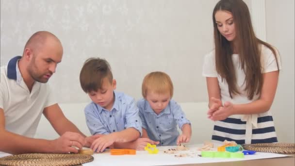 Les jeunes parents enseignent à leurs petits garçons comment faire des cookies — Video