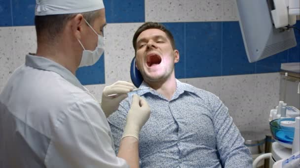 Пациент выходит из кабинета стоматолога, наслаждаясь результатом — стоковое видео