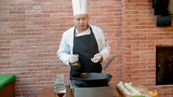 Bucătar turnând ulei vegetal în tigaie, vorbind cu o cameră foto — Videoclip de stoc