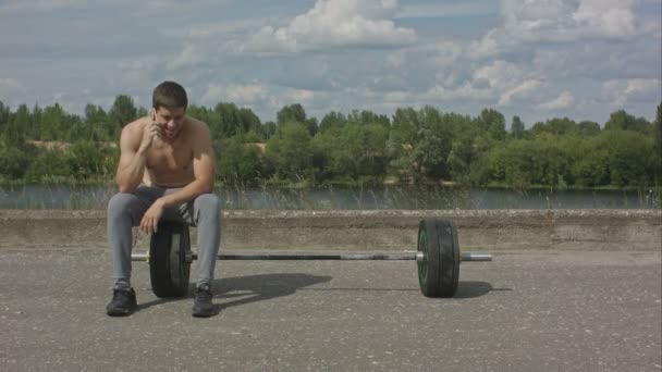 Athletic Brodaty mężczyzna z mięśni ciała mając telefon po treningu odkryty — Wideo stockowe