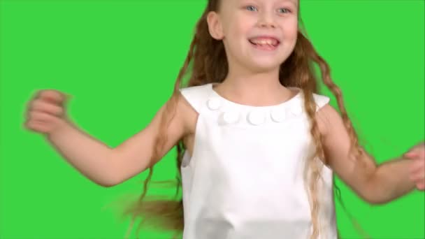 Граючи, стрибки маленька дівчинка в біле плаття насолоджується грою на зеленому екрані, ключ кольоровості — стокове відео