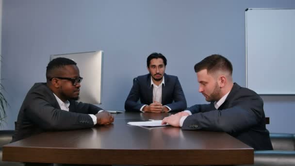 Young serious man holding papers, reading them attentively, during meeting in office — Stock Video