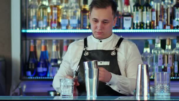 Бармен делает коктейль в баре, наливает в стакан из шейкера — стоковое видео