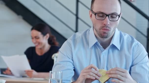 Genç iş adamı oturuyor ve ofiste peynir ile sandviç yiyor — Stok video