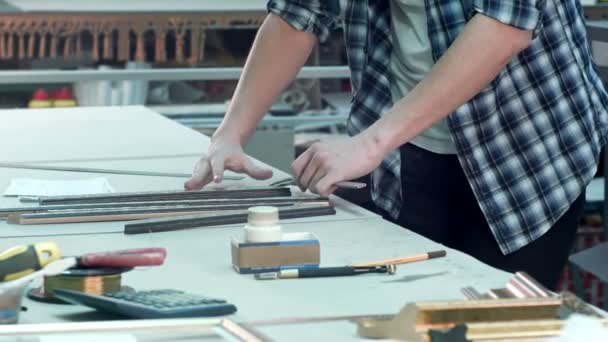 Jonge mannelijke werknemer op frame workshop werken aan balie — Stockvideo