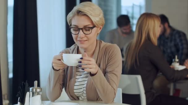 Молодая красивая женщина пьет кофе в кафе-баре — стоковое видео