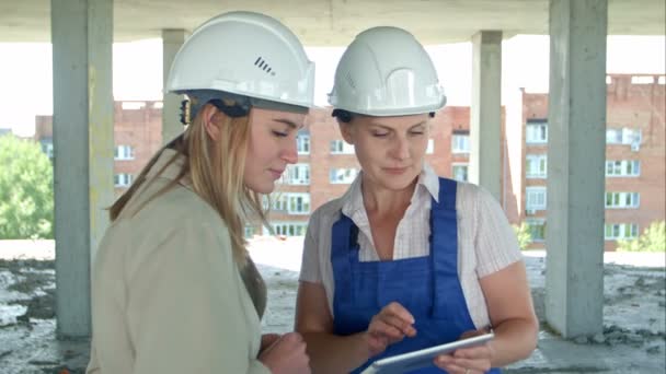 Engenheira e trabalhadora no canteiro de obras com plano em tablet digital — Vídeo de Stock