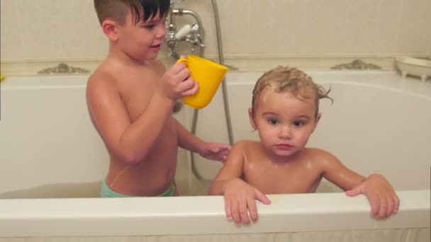 Маленький мальчик моет своего младшего брата в ванной — стоковое видео