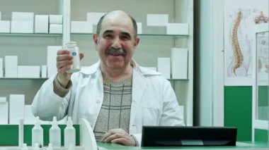 Bir şişe tablet advacing bir kamera için arayan müşteriler için tutan doktor gülümseyen