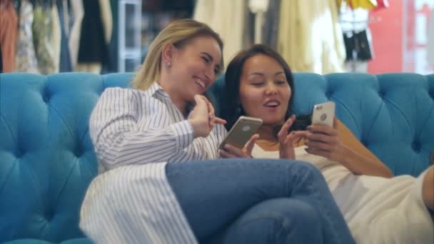 Gelukkig winkelen vrouwen gebruiken van smartphone en lachen zittend in winkelcentrum — Stockvideo