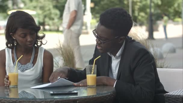 Αφρικανική αμερικανική επιχείρηση άτομα που κατέχουν έγγραφα, εξηγώντας τις λεπτομέρειες ενώ έχοντας μια συνάντηση στο καφενείο — Αρχείο Βίντεο