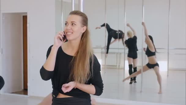 Fiatal nő van egy telefon hívás közben egy pole dance osztály