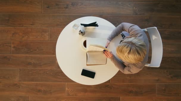 Zondagochtend levensstijl scène van jonge hipster vrouw leest haar notitieblok in café — Stockvideo