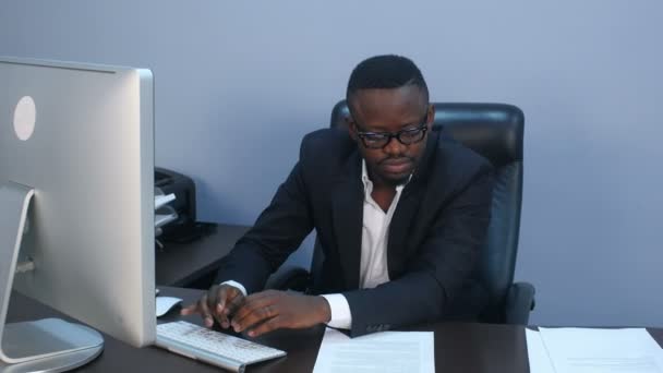 Portrait of young serious afro-american businessman working with laptop and document — Stock Video