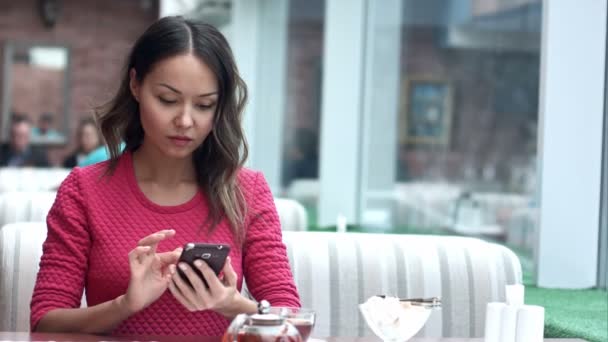 Mujer asiática mirando el teléfono celular y tomando té en la cafetería — Vídeo de stock