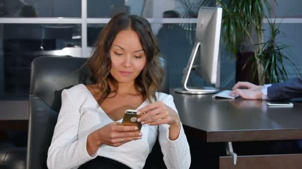 Молода азіатська бізнес-леді використовує мобільний телефон в офісі — стокове відео