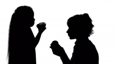 Silhouette portre genç bir anne ve onun küçük kızı elma parça mat yeme